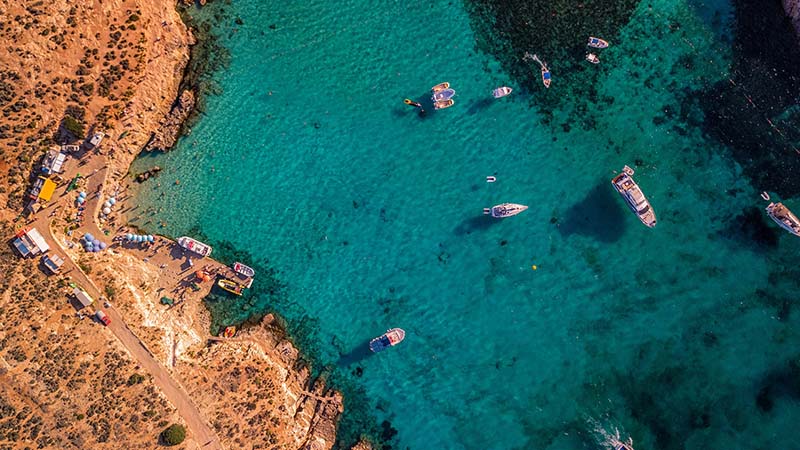 Aerial view of turquoise water and anchored boats in Comino